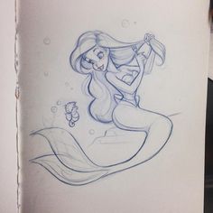 a drawing of a little mermaid sitting on top of a piece of paper with a fish in it's mouth