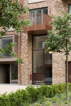 an apartment building with trees and bushes in front