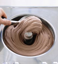 a person mixing chocolate in a metal bowl