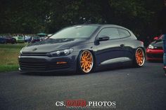 a black car with orange rims parked on the street