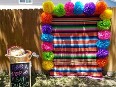 a colorful display with tissue pom poms in front of a fence