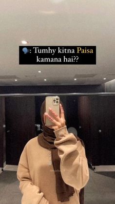 a woman wearing a hijab taking a selfie with her cell phone in an elevator