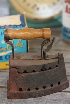 an old iron with a wooden handle on top of it next to some boxes and other items