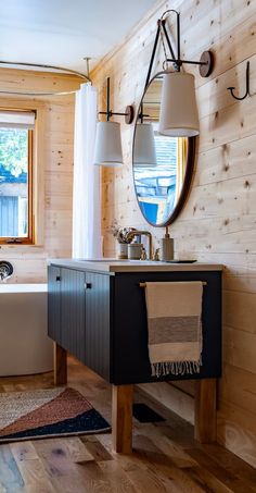 a bathroom with a tub, sink and mirror