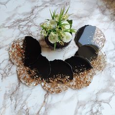 there is a flower pot and some cookies on the marble counter top with gold flakes