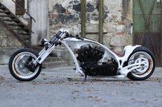 a white and black motorcycle parked on the side of a road next to stairs in front of an old building