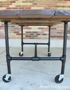 a table that has wheels on it and is made out of wood with metal pipes