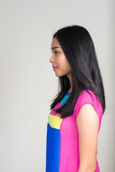 a woman with long black hair wearing a pink and blue shirt