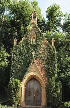 an old church with ivy growing all over it's roof and door, surrounded by trees