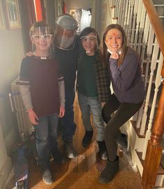 three girls and one boy are standing on the stairs with their faces covered by masks