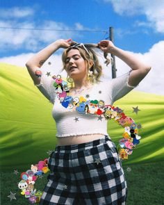 a woman is standing in the grass with her hands on her head and she has buttons all over her body