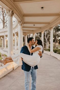 a man holding a woman in his arms while she kisses her cheek on the cheek