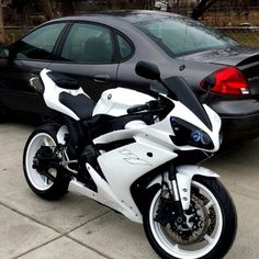 a white and black motorcycle parked next to a car