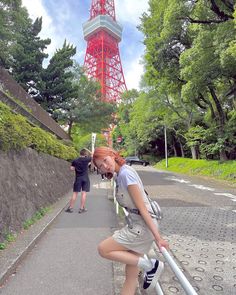 a woman leaning on a pole in front of the eiffel tower