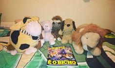 several stuffed animals sitting on top of a bed next to a book with the cover pulled down