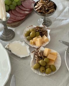 three plates filled with cheese, olives and nuts on a table next to other food