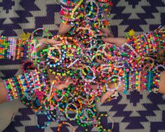 several hands holding colorful bracelets on top of a purple and white carpeted floor