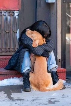 a person sitting on the ground hugging a dog