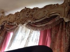 an ornately decorated bedroom with pink drapes and curtains on the window sill