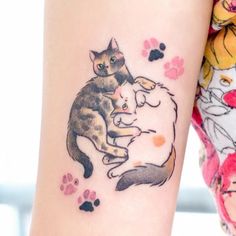 a woman with a cat tattoo on her arm next to a dog and cat paw prints