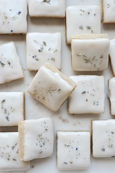 several square pieces of soap sitting on top of a white surface with lavender and rosemary sprinkles