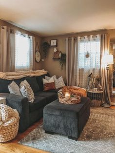 a living room filled with lots of furniture next to a window covered in curtains and pillows