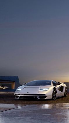 a white sports car parked in front of a building at night with the sun setting