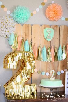a birthday party with gold and mint green decorations, tissue pom poms and paper flowers