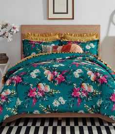 a bed covered in a blue floral comforter and matching pillow cases with gold trim