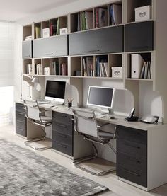 a home office with two computer desks and bookshelves in front of it
