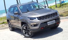 a grey jeep is parked on the side of the road near the ocean and palm trees