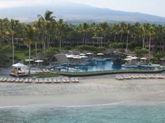 an aerial view of the resort and pool area with lounge chairs, umbrellas and palm trees