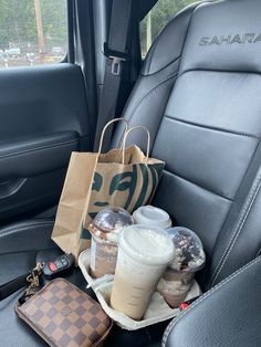the back seat of a car is filled with food and drinks, along with a brown paper bag
