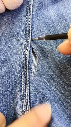 someone is using a sewing needle to sew on some jeans