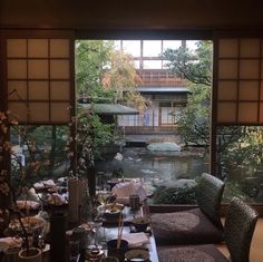 a dining room table is set with place settings and flowers in front of the window