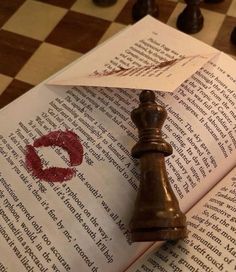 a book with a piece of paper on top of it next to a chess board
