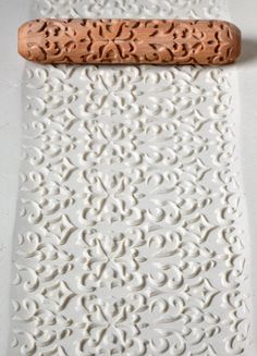 a white wall with a wooden handle on it's side and an intricate design
