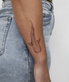 a woman's arm with a tattoo on it that has an image of a fish