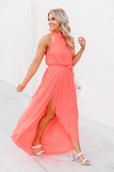 a woman in an orange dress is walking down the street with her hand on her hip