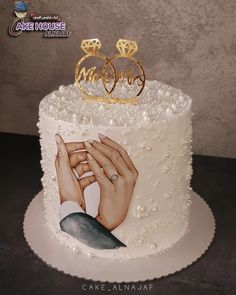 a wedding cake decorated with two hands holding the bride's hand and diamond rings