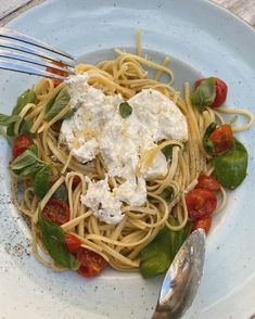 a plate of pasta with spinach, tomatoes and fettuccine on it