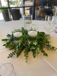 Greenery centerpiece, simple centerpiece, wedding, candles Flameless Floating Candle Centerpieces, Lily Pad Table Decorations, Simple Green Centerpiece Wedding, Simple Banquet Centerpieces, Greenery And Candle Centerpiece, Candle And Greenery Centerpiece, Eucalyptus Candle Centerpiece, Floating Candles Wedding Centerpieces, Floating Candles Centerpieces