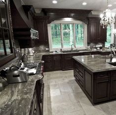 a large kitchen with granite counter tops and dark wood cabinets