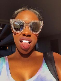a woman wearing sunglasses making a funny face with her tongue out and tongue hanging out
