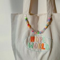 a white bag with beaded words and beads hanging from it's side on a wall