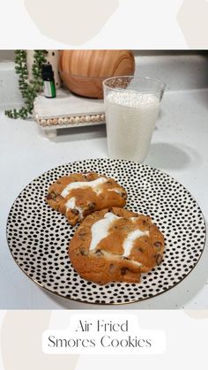 two cookies sitting on top of a black and white plate next to a glass of milk