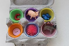 an egg carton filled with lots of different colored plastic cups and animals in them