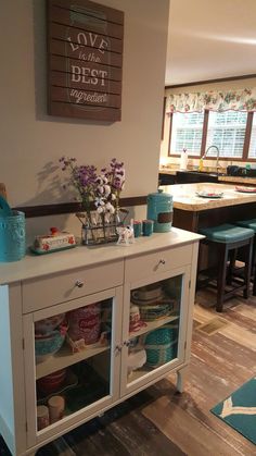 a white cabinet filled with lots of dishes and vases on top of it's sides