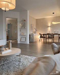 a living room filled with furniture next to a dining room table and chairs on top of a hard wood floor