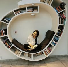 a woman sitting on a couch in front of a bookshelf filled with books